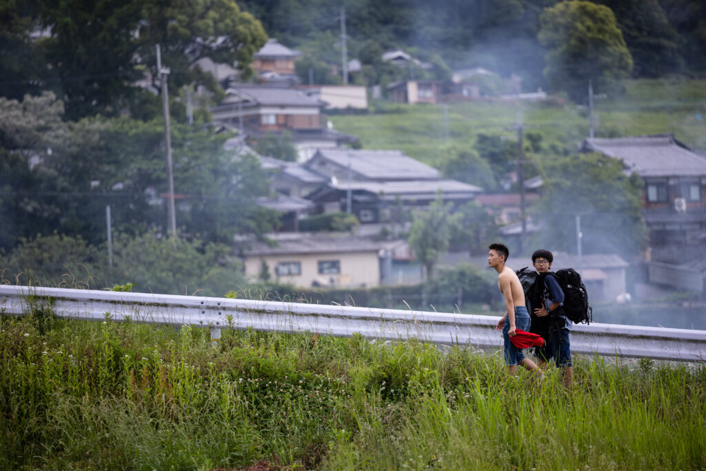 Two Japanese teenagers walking up the hill in the suburbs