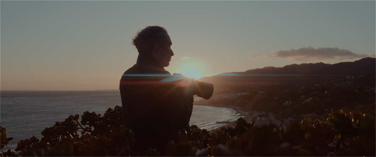 Photographer standing atop Santa Monica hills looking out to the sunset over the Pacific Coast.