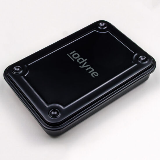 3/4 view from top of a small, black steel case with pronounced divots to accept feet for stacking multiple cases neatly. case is oriented vertically, with the iodyne logo printed in medium gray along the short axis, slightly above the middle vertically