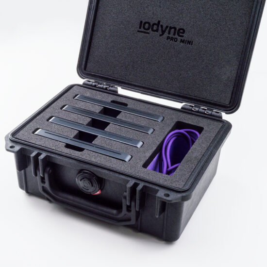 A black, toolbox-sized Pelican case is open to reveal custom closed-cell foam with four horizontal slots populated with Pro Mini devices at left, and a wider vertical slot containing Thunderbolt cables and other Pro Mini accessories