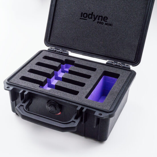 A black, toolbox-sized Pelican case is open to reveal custom closed-cell foam with four horizontal slots Pro Mini devices at left, and a wider vertical slot for cables and other Pro Mini accessories. In the lid is another layer of protective foam with a small etched "iodyne Pro Mini" logo oriented horizontally