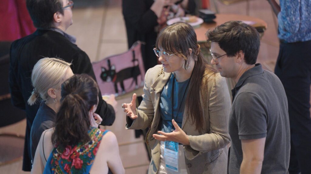 three women and a men chatting at a crowded conference