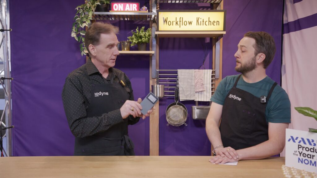 Film professionals discussing in Workflow Kitchen set and showing a portable data storage device