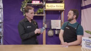 Film professionals discussing in Workflow Kitchen set and showing a portable data storage device