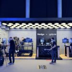 DIT carts, cameras, and monitors set up at a tradeshow for video production, and exhibitors meeting attendees